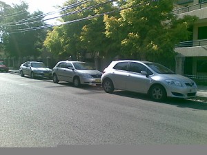 3 silver Corollas of various vintages all parked in a row 3 silver Corollas of various vintages all parked in a row