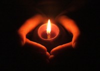 Hands cupping a burning candle